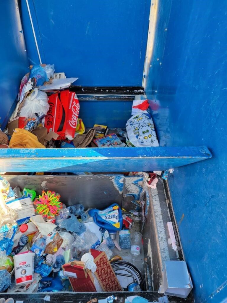 Photograph of interior of a blue recycling truck with two compartments filled with recyclable materials.