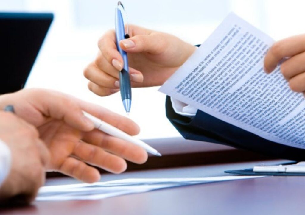 Close up on hands holding pens, editing paper documents.