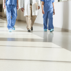 Three healthcare professionals walk down a hospital hallway in scrubs. We see them from the waist down.