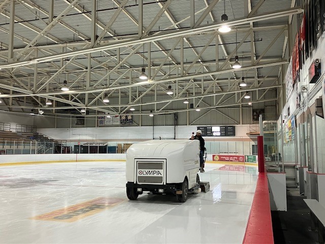 man driving ice resurfacer on a hockey rink