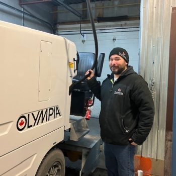 Man holding hose to insert gas into an ice resurfacer